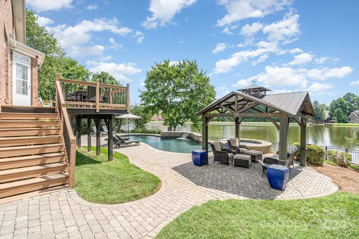 Private patio with gazebo, inground pool, waterfall, and hot tub.