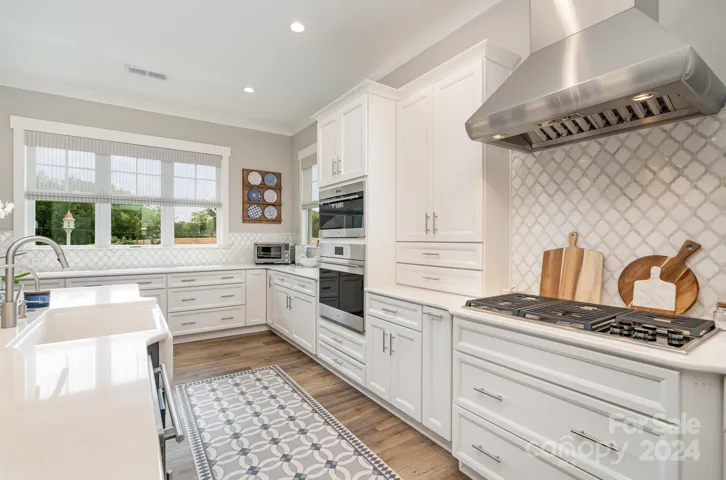 Chefs kitchen featuring gourmet appliances. Note the Wolf Cooktop and Hood, Wolf Ovens, Core Dishwasher.