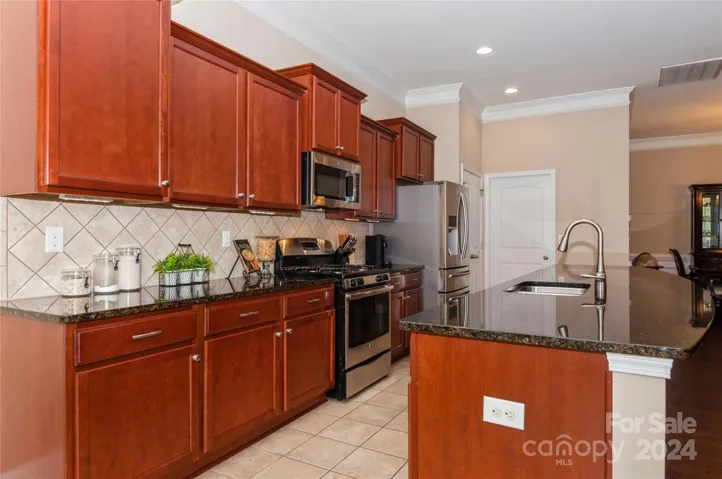 Kitchen with lots of cherry cabinets and tile backsplash.