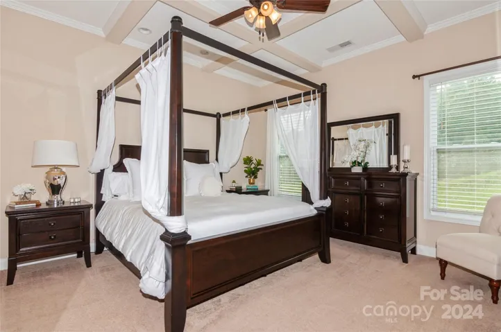 Primary Suite with coffered tray ceiling and ceiling fan.