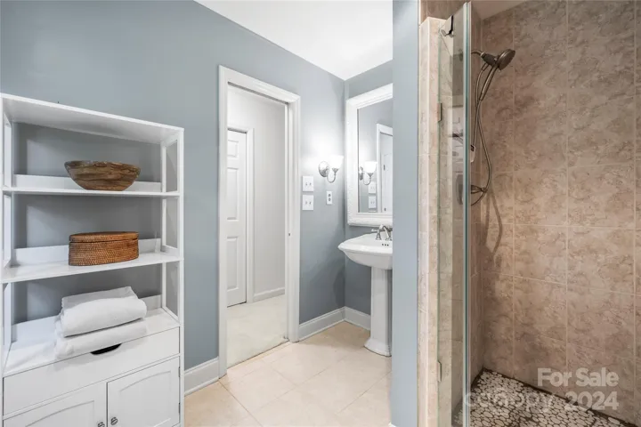 The lower level primary bath features tile flooring and a pedestal sink