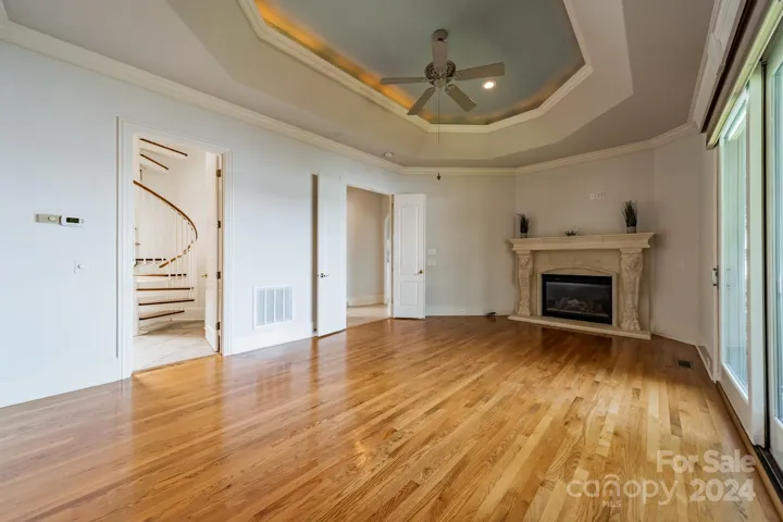 Main level primary bedroom with tray ceilings, a fireplace and a spectacular window with lake views
