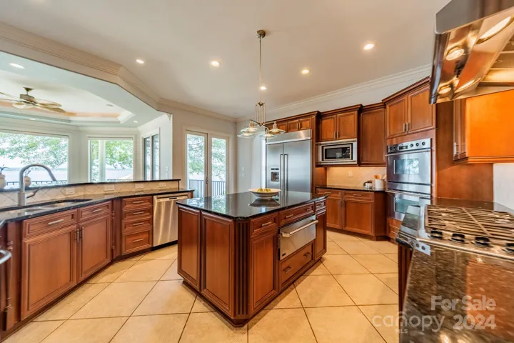 Open concept kitchen with breakfast and family room which open to a wall of windows to view the lake.