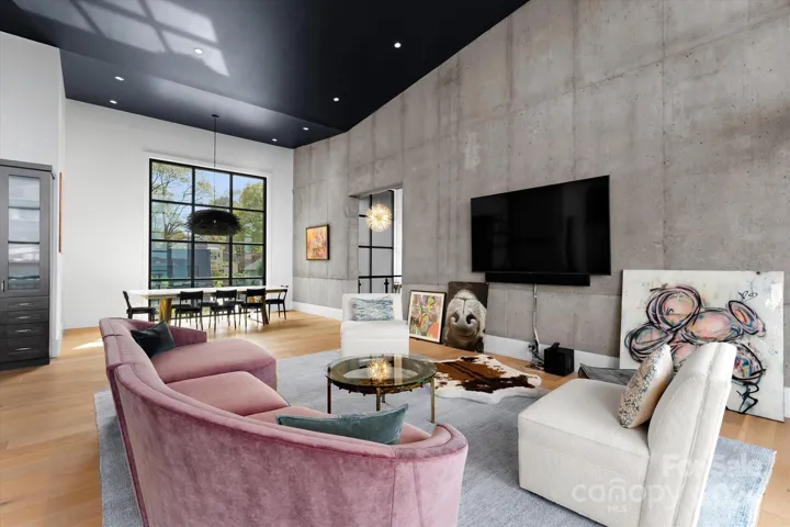 The open-concept family room, kitchen, and dining area are anchored by a striking one-foot-thick concrete feature wall, serving as both a bold architectural statement and a work of art.