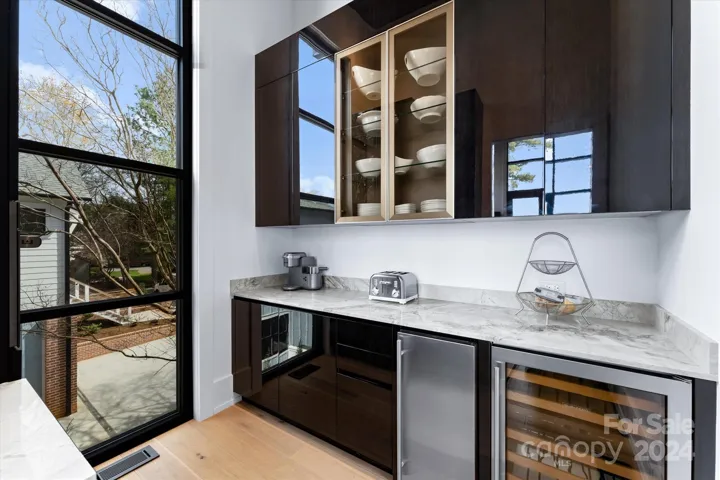 The scullery featuring a wine cooler, microwave, ice maker, and sleek cabinetry.