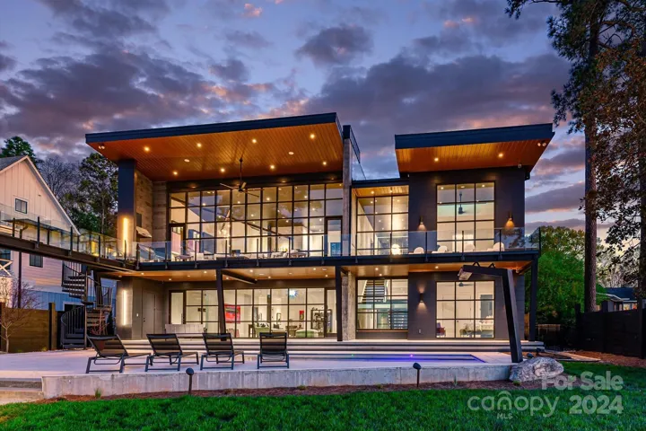 At sunset, walls of windows illuminate this ultra-contemporary home, with the lights creating a stunning display against the modern architecture.