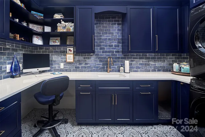 Laundry room has it all!  Counter height desk, file storage, stacked W/D, gift wrapping cabinet, and even a spot for man's best friend.