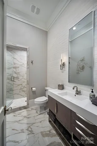 En suite for BR #2 has heated floors, shower with bench, and faux brick wall behind James Martin Vanity.