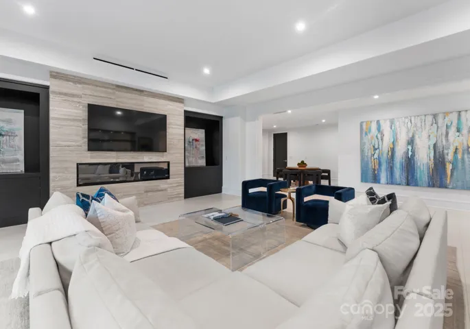 Lower level living area with linear modern fireplace, custom glass display case and leading out to lower level covered patio