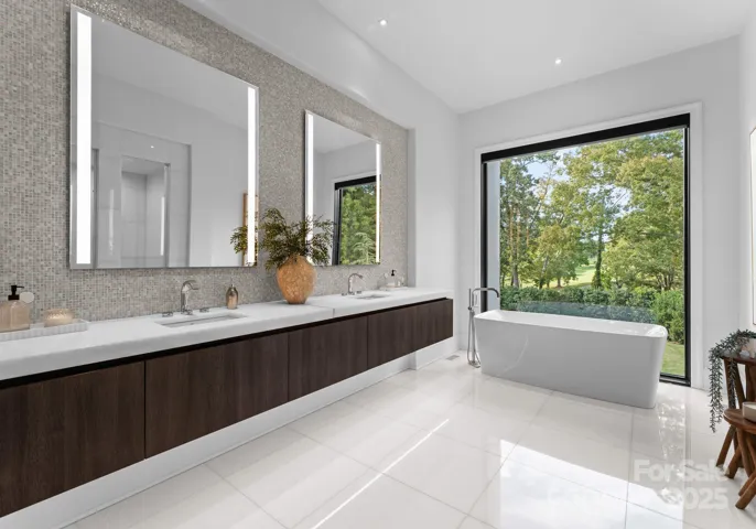 Primary bathroom with heated floors and modern soaking tub overlooking private backyard