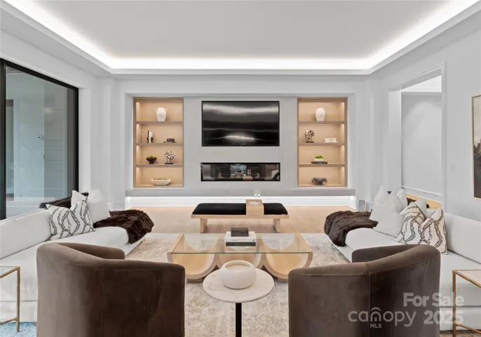 Great Room opening to outdoor covered and patio and built-in grilling area. Accented with custom built-in's and linear fireplace with elegant plastered surround