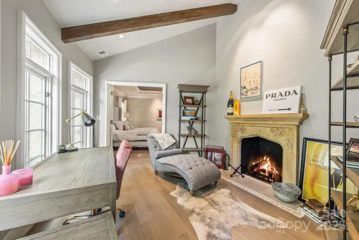 The beamed ceiling frames this cozy sitting room or second office space with a limestone carved mantle.