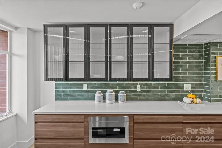 Glass front cabinetry with interior lighting. Note the microwave drawer
