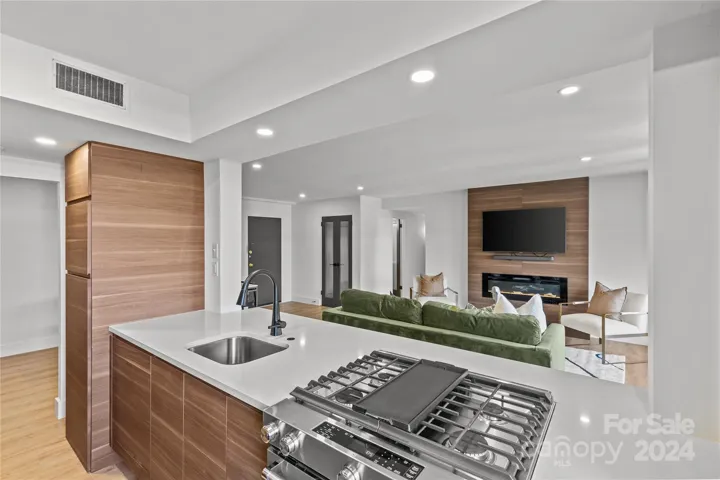 Gas range with griddle, dishwasher has custom panel to match cabinetry, washer/dryer is enclosed in cabinetry.