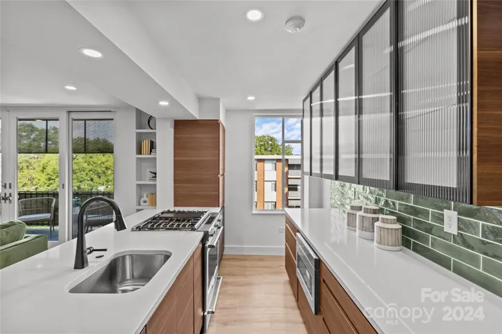 Gorgeous modern kitchen offers quartz counters, walnut inspired cabinetry, refrigerator has custom paneled front to match cabinetry.