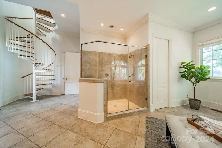 Primary bathroom shower, spiral stairs are a 2nd entrance to the workout room