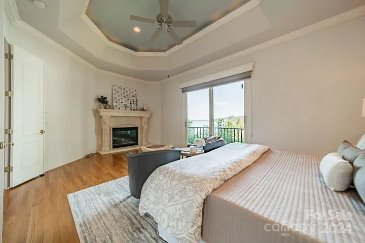 Primary bedroom with tray ceiling, Lake view and fireplace