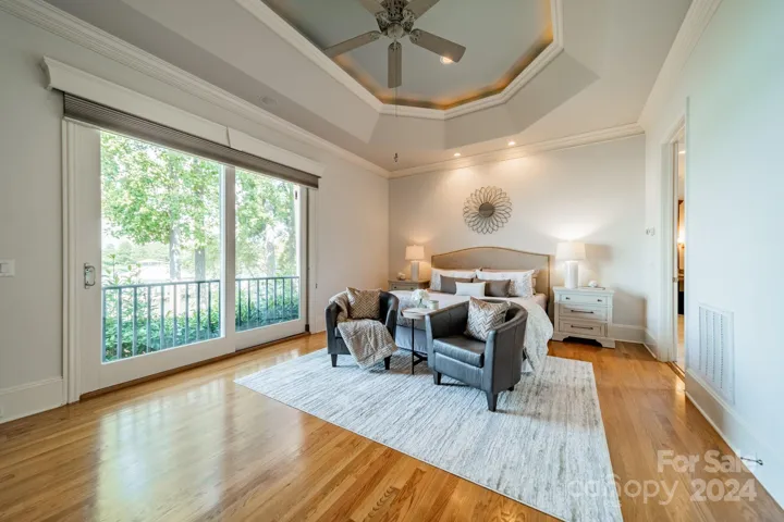 Main level Primary bedroom with tray ceiling, fireplace and lake views