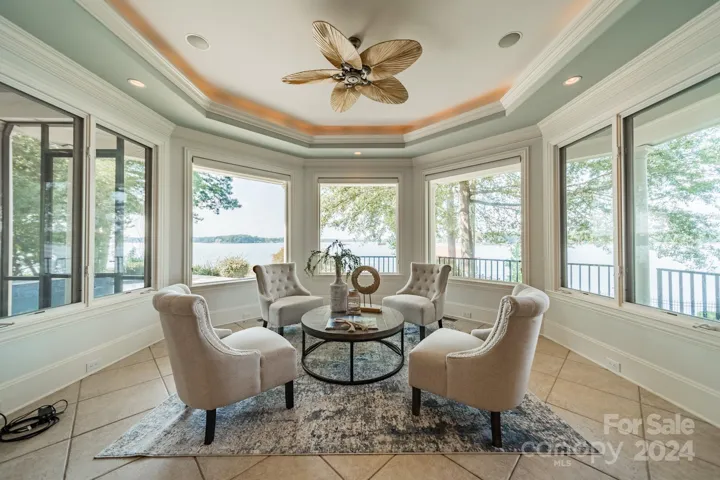 Sitting area surrounded by windows to take in the view. Open concept to the kitchen and breakfast area