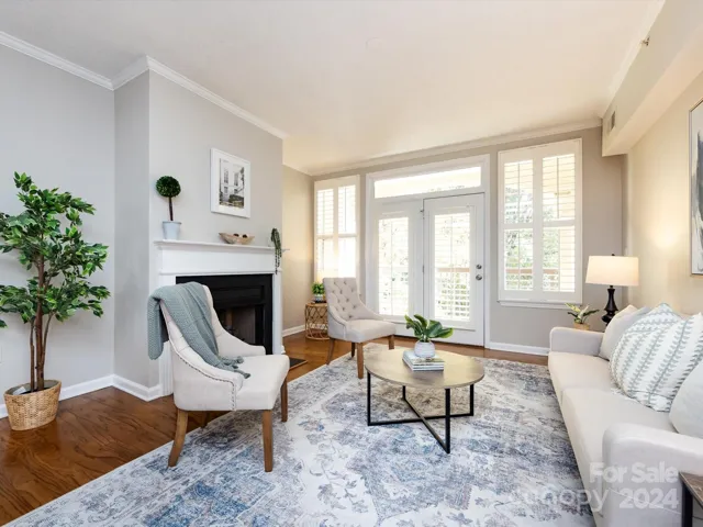 Living Room with gas fireplace, crown molding & balcony access with plenty of natural light & plantation shutters!