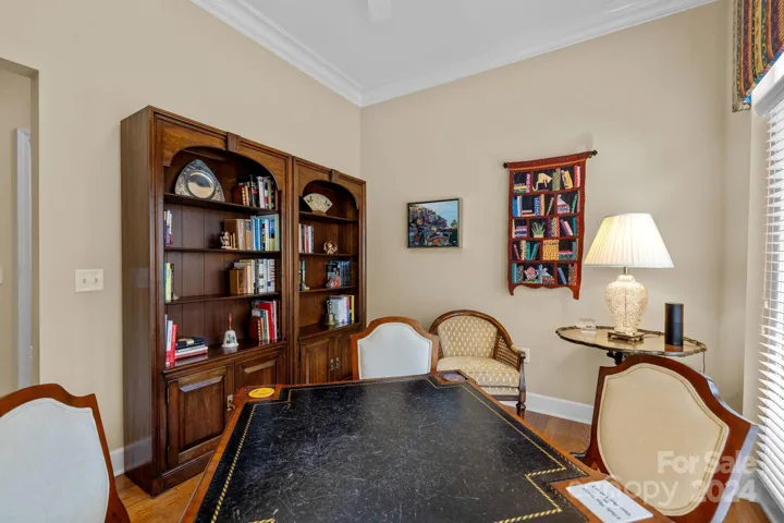 Den features hardwood floors, crown molding, ceiling fan, room for a large screen TV.
