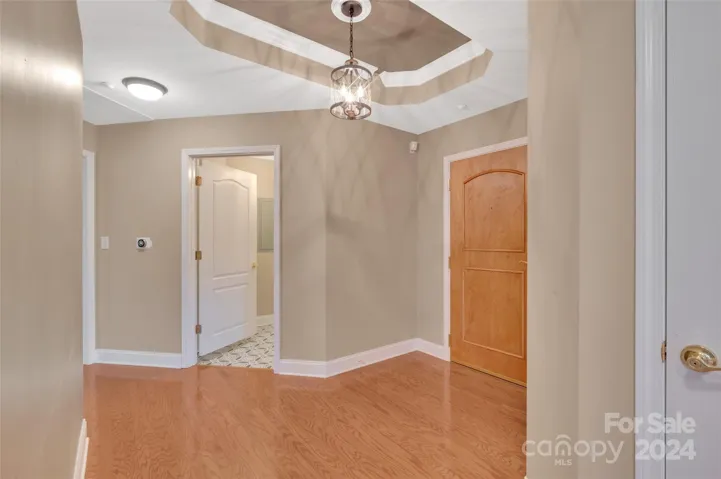 Welcoming large, entrance foyer with trayed ceiling looking towards the laundry/utility room.