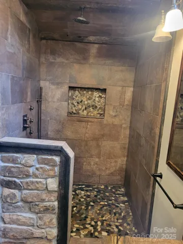 Primary bath features rustic stone, tile, RR tie look with stone floor & cut-out.