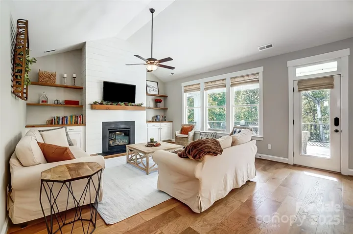 Vaulted great room with gas fireplace, built-ins, and access to covered patio with electric remote screen