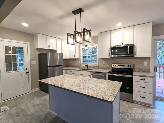 Kitchen has tile floors, gorgeous cabinets, stainless steel appliances, granite countertops, and pretty light fixtures!