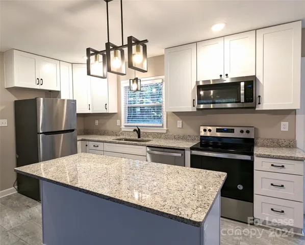 Kitchen has tile floors, gorgeous cabinets, stainless steel appliances, granite countertops, and pretty light fixtures! Window over the sink looks out into backyard.