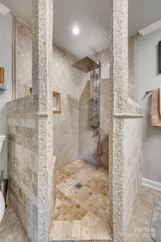 Step into a haven of modern luxury with a spacious walk-in shower featuring a rainfall shower tower panel system.