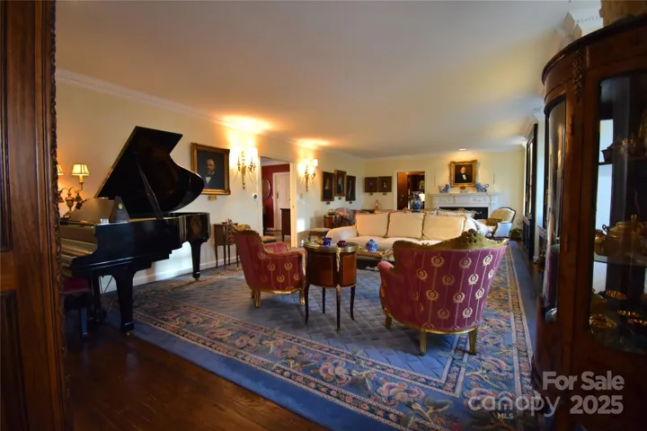 Living room large enough to seat ten comfortably and a baby grand piano.