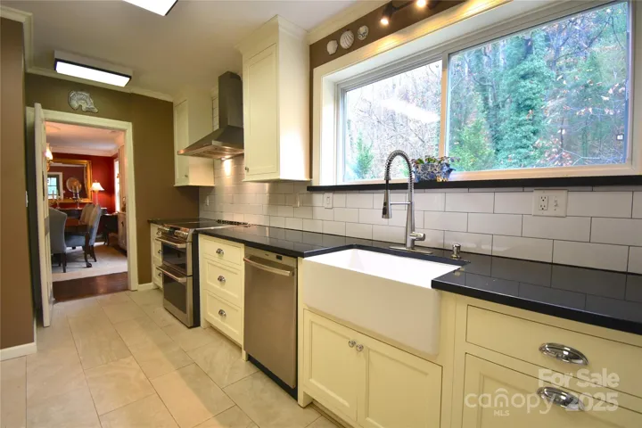 Updated Kitchen features custom cabinetry with dark stone countertops and large cast iron farm sink.