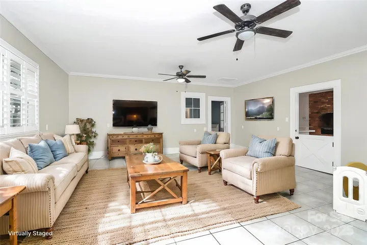 virtually staged family room features dual ceiling fans and tile flooring.