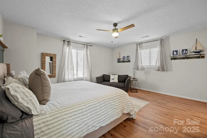 Spacious Primary Bedroom features ceiling fan/light, custom molding, LVP floors, private bath & walk in closet!