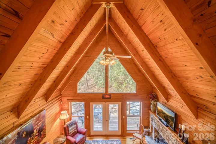 Dramatic vaulted great room with floor-to-ceiling windows and stone woodburning fireplace