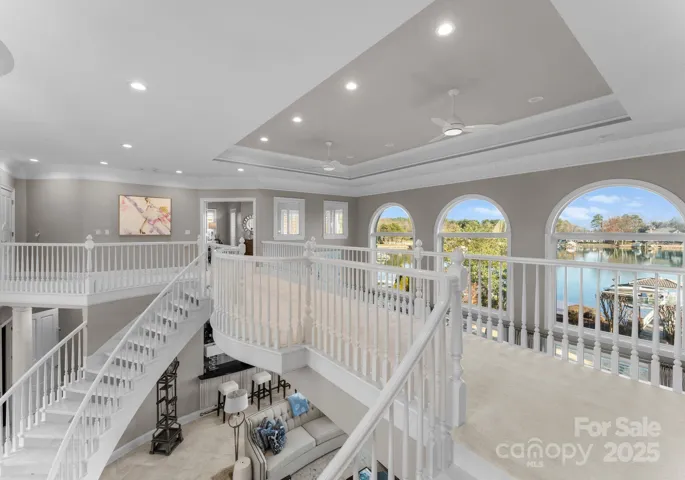 The upper level offers a stunning vantage point of the foyer, great room, and catwalk, with expansive windows framing picturesque views of the lake beyond. The design creates an open and airy feel, with a seamless connection to the beauty of the outdoor surroundings.