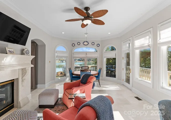 The sitting area with a cozy fireplace and the adjacent kitchen table are perfectly positioned to capture serene lake views through large windows, creating an inviting space for both relaxation and dining.