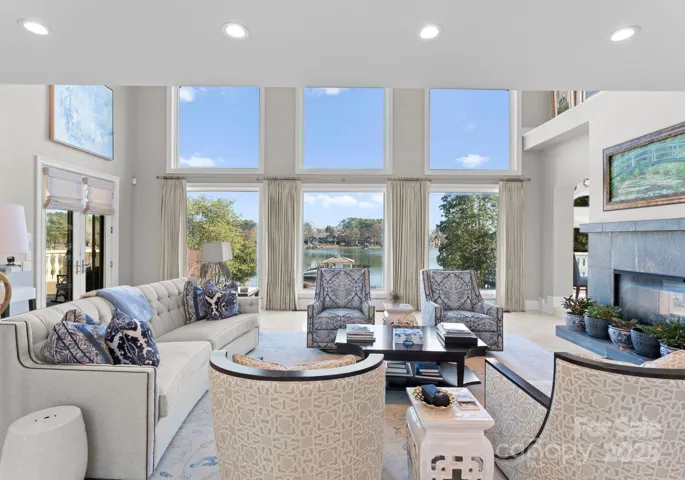 Great room with soaring windows that allow natural light to flood the space and a dual sided fireplace.