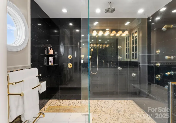 The primary suite boasts a spacious walk-in shower, designed with classic elegance and luxurious finishes, providing a serene and inviting atmosphere.
