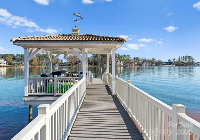 A stylish dock featuring a covered seating area, complete with a ceiling fan for added comfort, offering the perfect spot to relax and enjoy lake views.