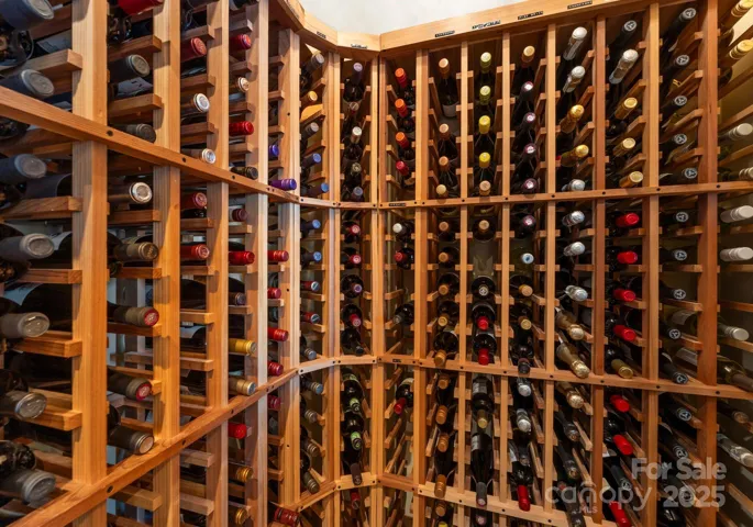 The wine room is a true statement piece, featuring an elegant glass door adorned with intricate grape and vine designs, creating a stunning focal point.