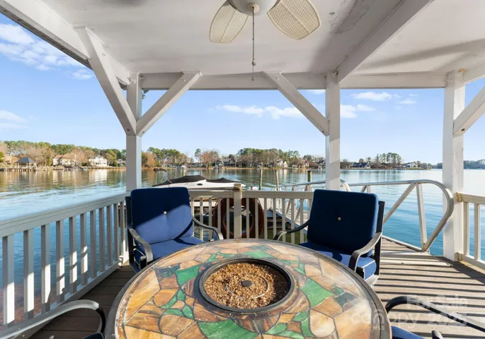 A stylish dock featuring a covered seating area, complete with a ceiling fan for added comfort, offering the perfect spot to relax and enjoy lake views.