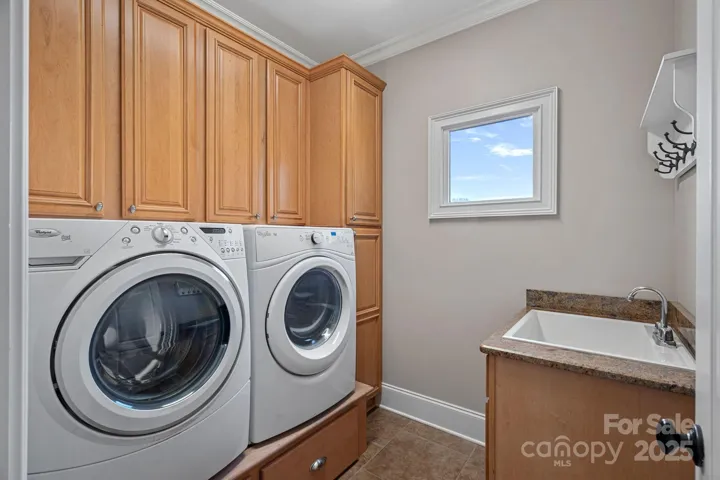 Laundry room accessed off garage and adjacent to the kitchen with custom cabinetry and built-in washer/dryer pedestals...large farm sink.