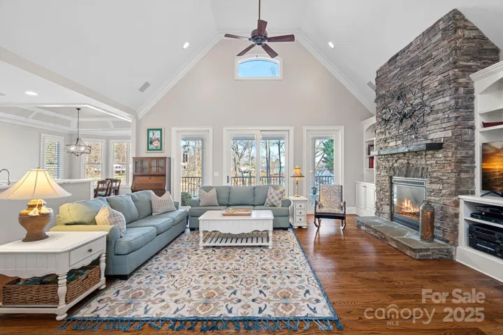 Stunning living room with vaulted ceiling, full-height stone fireplace, built-ins, and lake views!