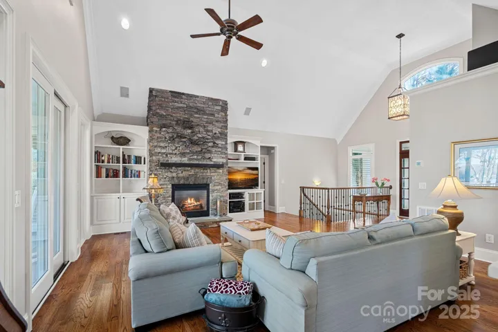 Stunning living room with vaulted ceiling, full-height stone fireplace, built-ins, and lake views!