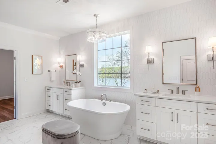 Primary bath with dual vanities, soaking tub, and natural light.