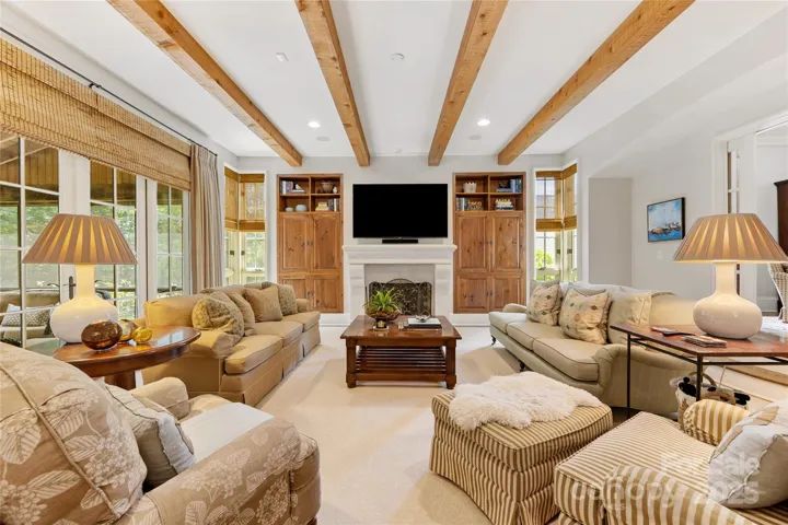 Custom built-ins, a cast stone fireplace, & a beamed ceiling are the highlights of this family room.