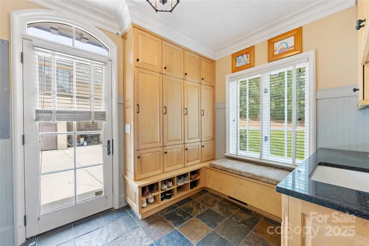 A spectacular laundry room boasts drop-zone style lockers, a bench seat & a door to the parking pad area.