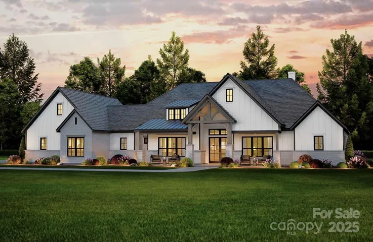 This stunning modern farmhouse features a crisp white exterior with board-and-batten siding, contrasting dark trim, and a welcoming covered front porch accented by timber beams and brick columns.